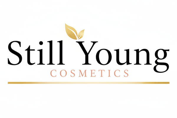 The logo for Still Young Cosmetics is centered on a solid white background. The brand name 'Still Young' is written in a black serif font, with a small gold leaf graphic above the 'Y'.